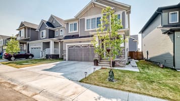 A two-story residential house with a garage, a driveway, and a well-maintained lawn.