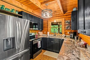 A modern kitchen with stainless steel appliances, dark cabinetry, and a wooden ceiling. - Cabin w/ Hot Tub · Hear the Dollywood Whistle (Sevierville)
