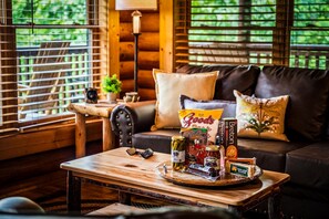 A cozy living room with a wooden coffee table, a leather sofa, and a window with blinds. - Cabin w/ Hot Tub · Hear the Dollywood Whistle (Sevierville)