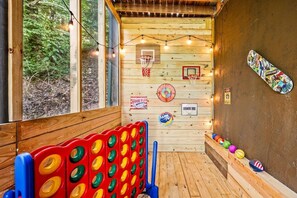 A wooden room with a basketball hoop, a dartboard, and a Moon Pie sign. - Cabin w/ Hot Tub · Hear the Dollywood Whistle (Sevierville)