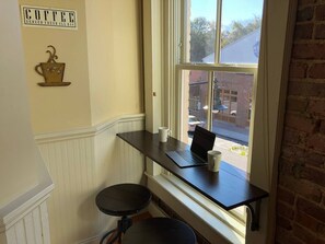 A small workspace with a laptop, two mugs, and a coffee cup decoration on the wall. - Downtown Wake Forest Loft #2 (Wake Forest)