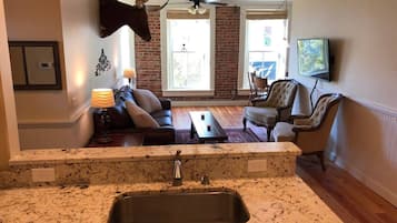 A kitchen with a granite countertop and a sink, a living room with a sofa and chairs, and a dining area with a table and chairs.