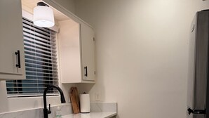 Una cocina con un lavamanos, armarios, una encimera y un refrigerador.