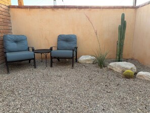 Eine Terrassenfläche mit zwei Stühlen, einem kleinen Tisch und einer Kakteenpflanze.