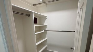 Un armario vestidor con estantes abiertos, barra para colgar ropa y puerta.