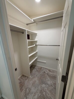 Ein begehbarer Kleiderschrank mit offenen Regalen, einer Kleiderstange und einer Tür.