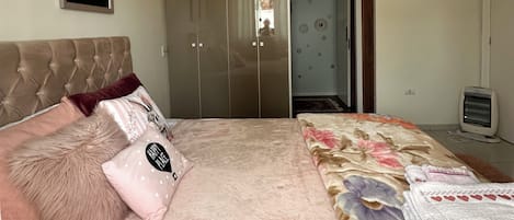Um quarto com uma cama, um guarda-roupa, um aquecedor e um quadro pendurado na parede.
