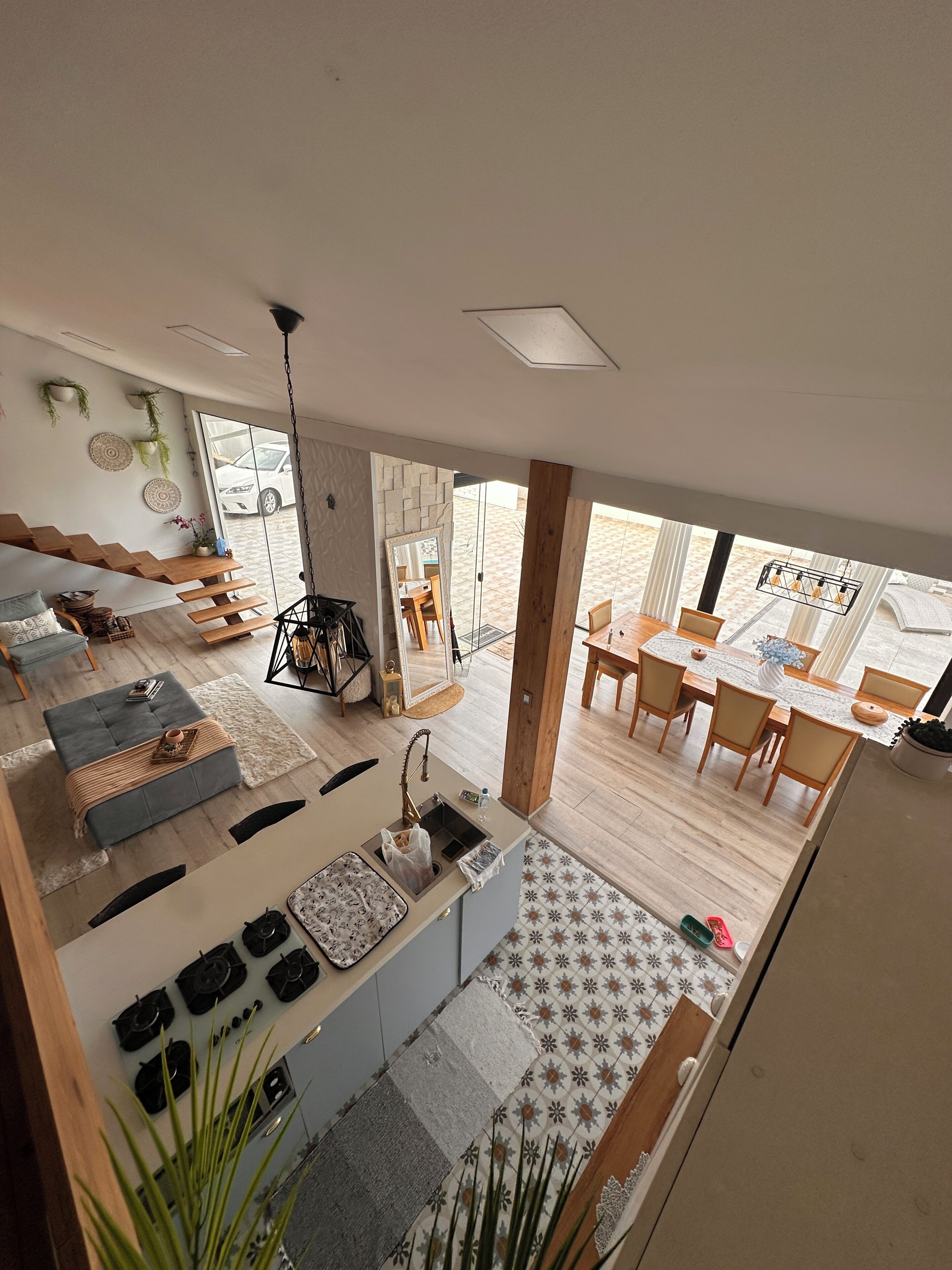 A modern kitchen with a central island, a dining area with a wooden table, and a view of the outside.