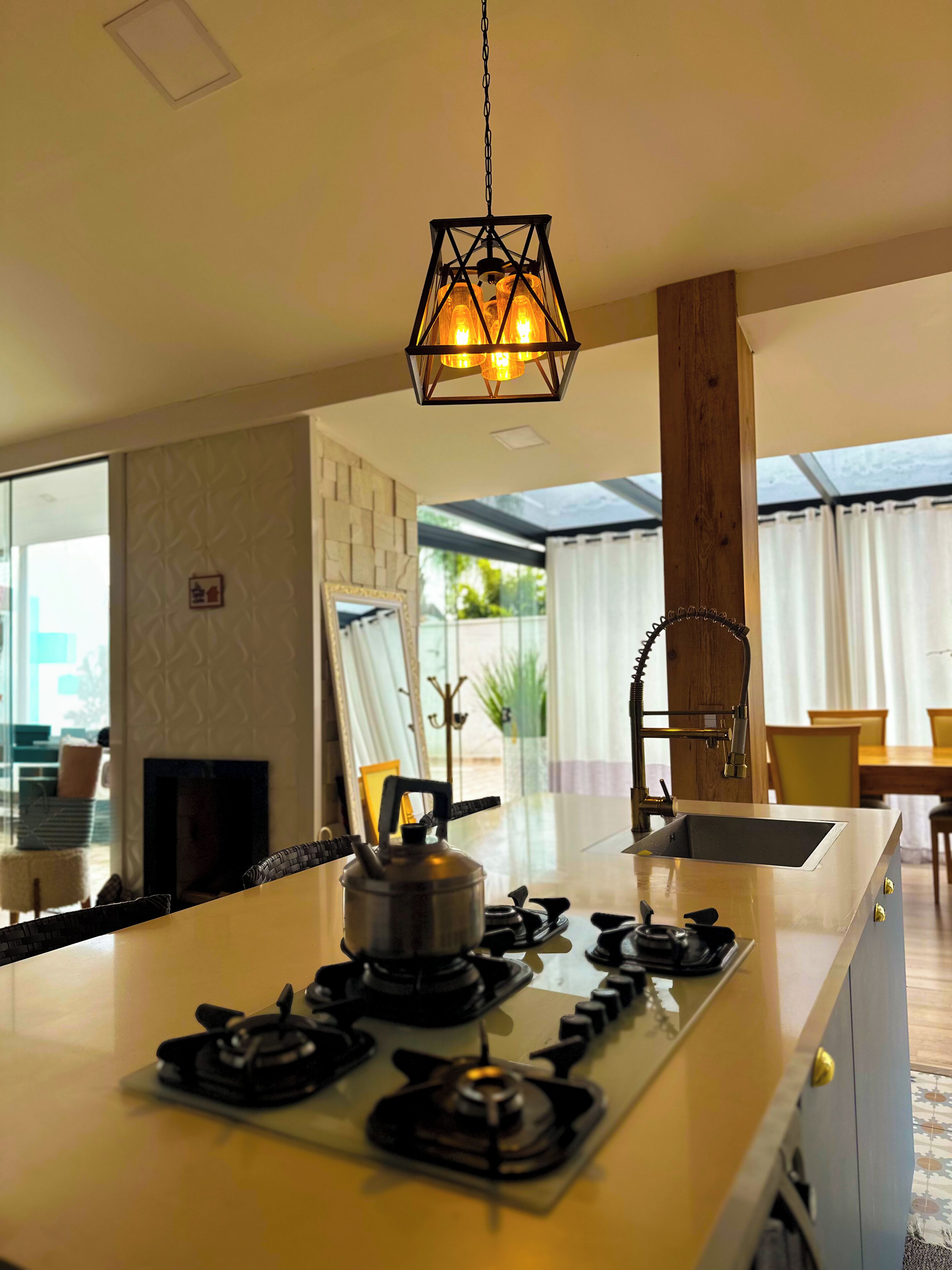 Une cuisine moderne dotée d’un îlot central, d’une cuisinière à gaz et d’un luminaire suspendu.