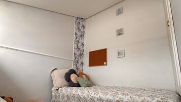 Un dormitorio con una cama, una alfombra mullida, un escritorio y un tablón de anuncios en la pared.