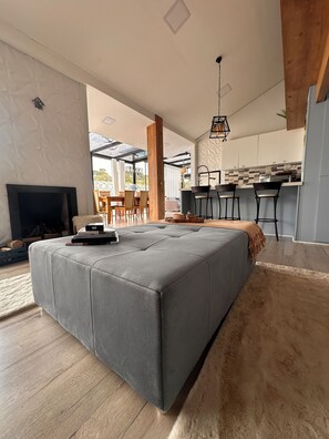 A modern living room with a grey sectional sofa, a fireplace, and a dining area with a wooden table and chairs.