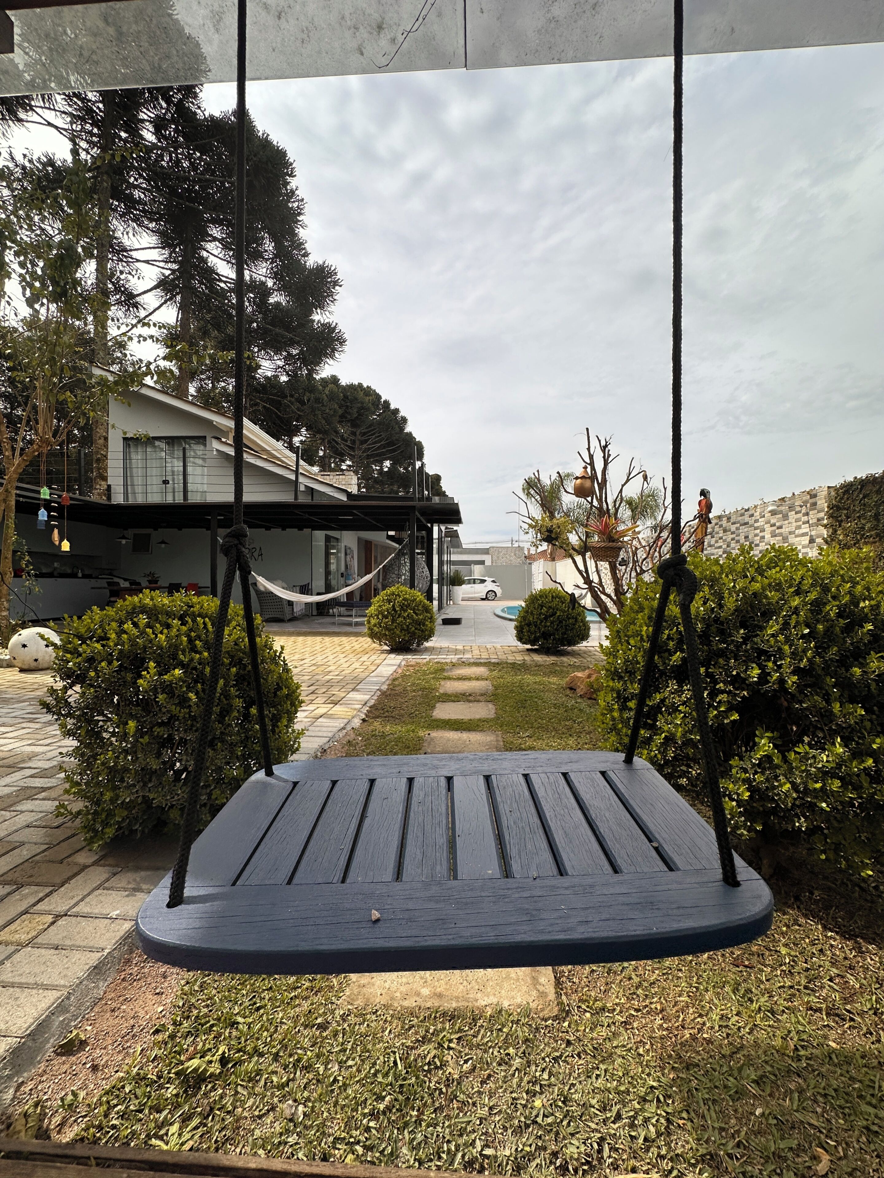 A patio area with a swing set, a pathway, and a building in the background.