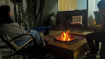Un espace extérieur aménagé avec un foyer, des chaises et une table.