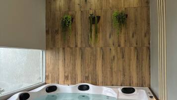 A modern bathroom with a freestanding bathtub, wooden panel wall, and recessed lighting.