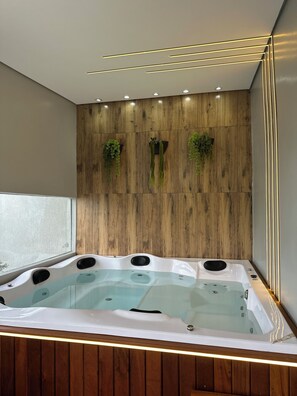 A modern bathroom with a freestanding bathtub, wooden panel wall, and recessed lighting.