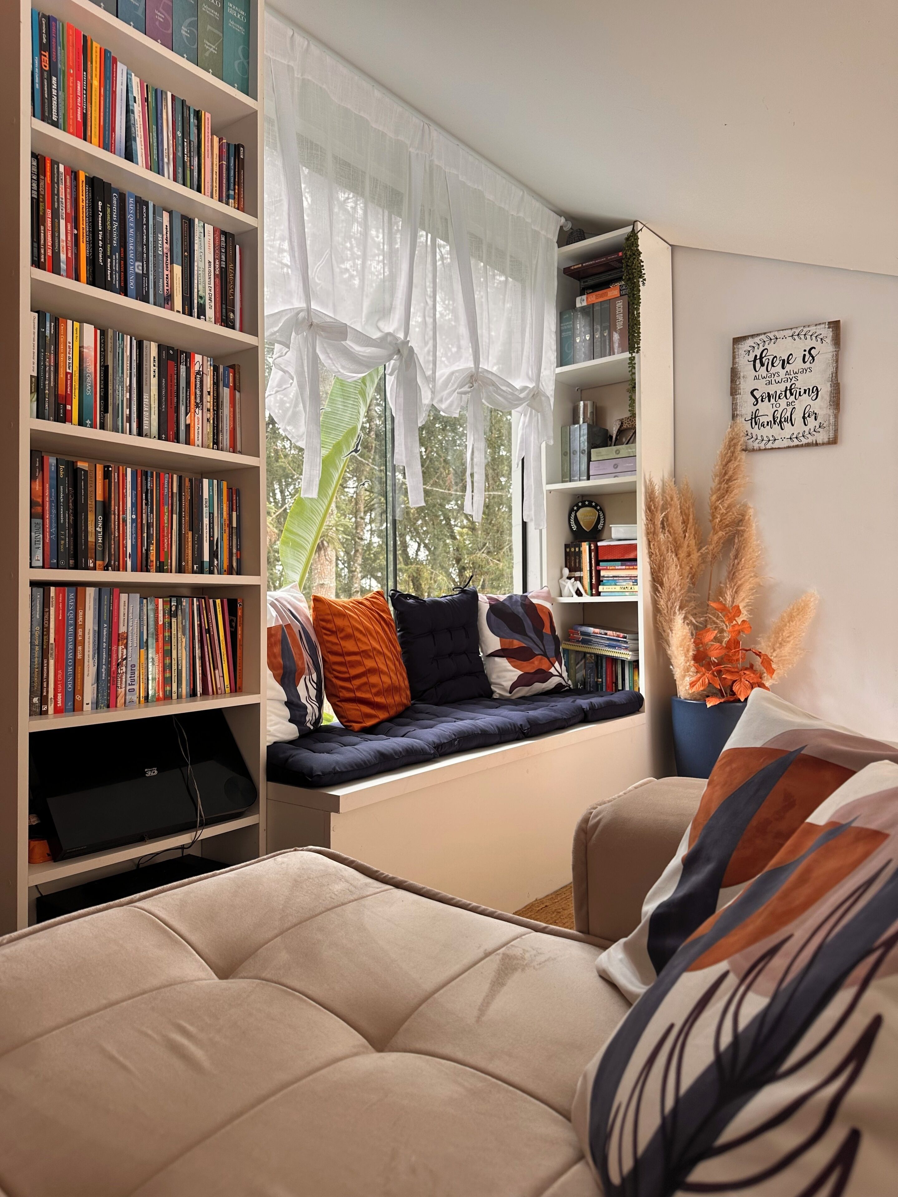 A cozy reading nook with a bookshelf, a cushioned bench, and a decorative sign.