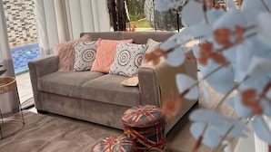 A modern living room with a sofa, patterned cushions, and decorative stools.