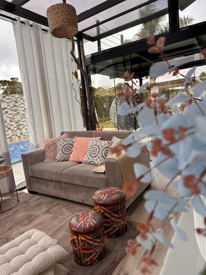 A modern living room with a sofa, patterned cushions, and decorative stools.