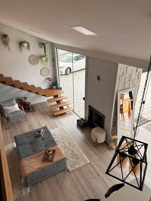 A modern living room with a sofa, a fireplace, and a view of the outside.