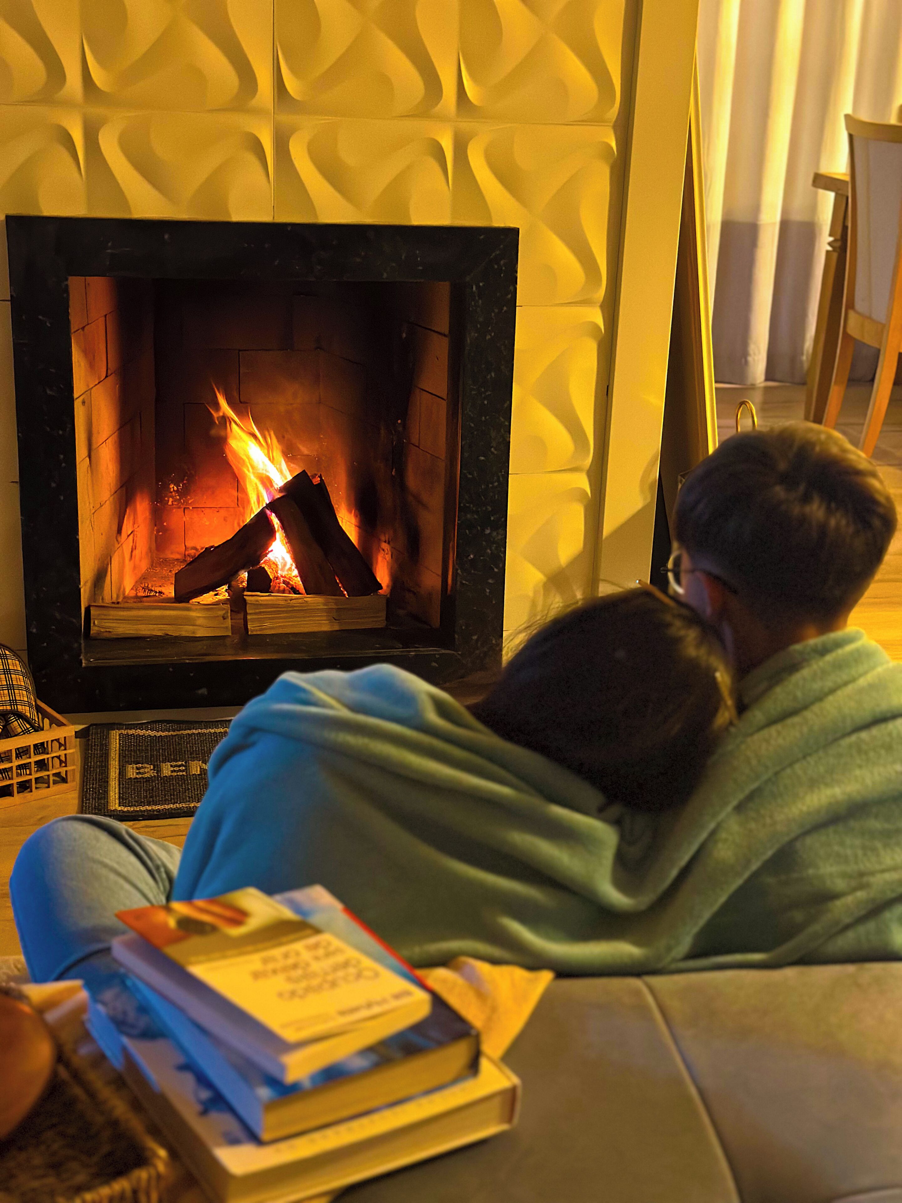 Ett rum med en öppen spis, en soffa och en person som sitter i soffan.