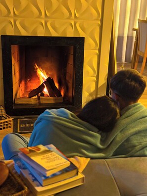 A room with a fireplace, a sofa, and a person sitting on the sofa.