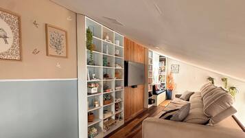 Una sala de estar moderna con un sofá, una estantería y un televisor de pantalla plana.