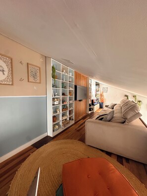 A modern living room with a sofa, a bookshelf, and a flat-screen TV.