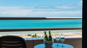 Ein Balkon mit Blick auf den Strand, ein Tisch mit zwei Flaschen und zwei Gläsern.