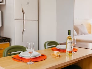 A dining table with a wine bottle, glasses, and a plate of cheese. - Terrazo Ponta Negra by Almare (Natal)