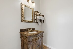 Een badkamer met een marmeren wastafel, een spiegel met gouden lijst en een handdoekhouder.