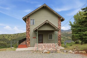 A two-story house with a stone facade, a front porch, and a visible staircase leading to the entrance. - Cozy 1BR casita with stunning panoramic views (Prescott)