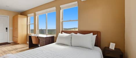 Een slaapkamer met een bed, een bureau en een stoel. Er is een airconditioner aan de muur.