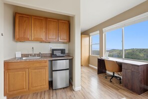A kitchen with wooden cabinets, a stainless steel refrigerator, a microwave, and a large window offering a view of the outdoors. - Cozy 1BR casita with stunning panoramic views (Prescott)