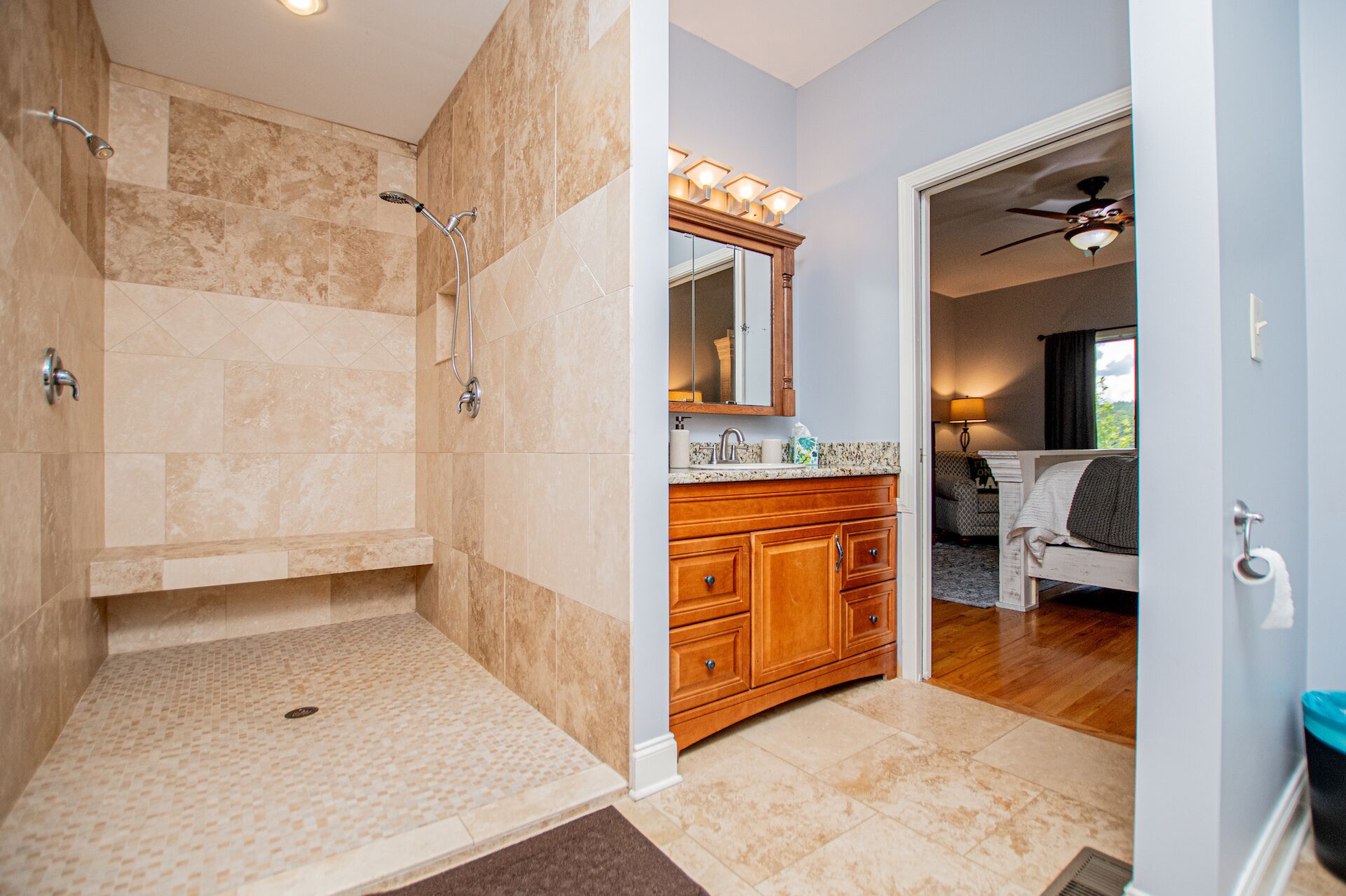 A bathroom with a shower, vanity, and a bedroom visible through an open door.