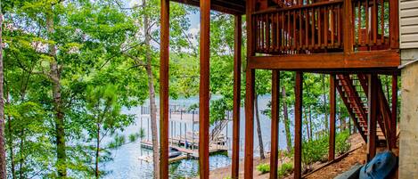 A wooden deck with a staircase leading to a dock over water, surrounded by trees.