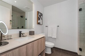 A modern bathroom with a large mirror, two sinks, a toilet, and a shower area. - Miami Downtown Balcon  Vista Espectacular (Miami)
