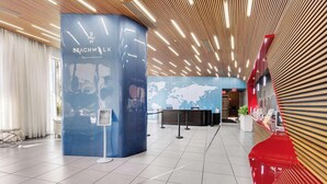 A modern lobby with a reception desk, a world map on the wall, and a sign indicating no swimwear or beachwear required. - Modern Studio Resort Style w/ Private Balcony (Hallandale Beach)