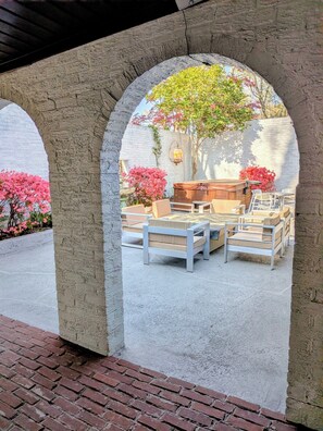 An outdoor patio with stone arches, a wooden table and chairs, and flowering plants. - The Chateau Elan of Atlanta with Courtyard Hot tub (Atlanta)
