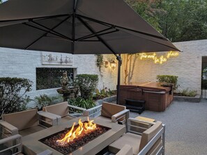 Eine Terrassenanlage im Freien mit Feuerstelle, Sitzgelegenheiten und einer Neonreklame.