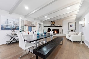 A modern living room with a fireplace, white furniture, and a dining area with a long table and chairs. - The Chateau Elan of Atlanta with Courtyard Hot tub (Atlanta)