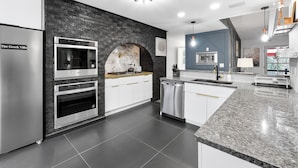 Una cucina moderna con una parete decorata in pietra, elettrodomestici integrati e un piano di lavoro in granito.
