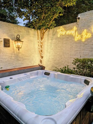 Un jacuzzi avec un arbre et une enseigne au néon en arrière-plan.