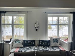 A room with a bed, two windows, a wall-mounted skull decoration, and pillows with logos.