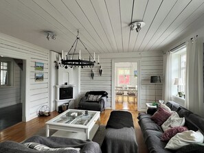 A spacious living room with a fireplace, a sofa set, a coffee table, and a chandelier.