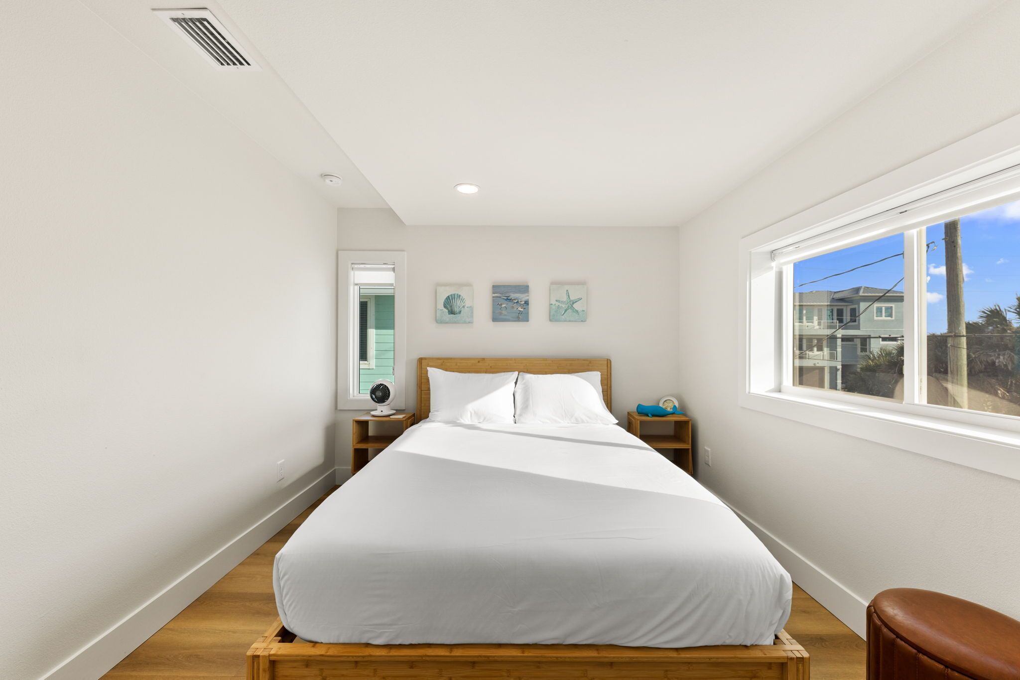 Un dormitorio con cama, ventana, mesita de noche y decoración en la pared.