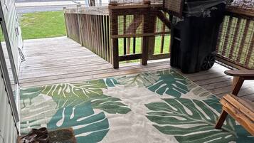 Ein überdachter Außenbereich mit Holzterrasse, einer Bank, einem Mülleimer und einem überdachten Tisch.