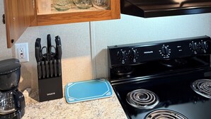 A kitchen with wooden cabinets, a stove, and various kitchenware.