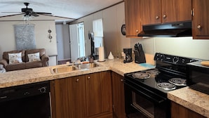 A compact kitchen with wooden cabinets, a black stove, and a granite countertop.