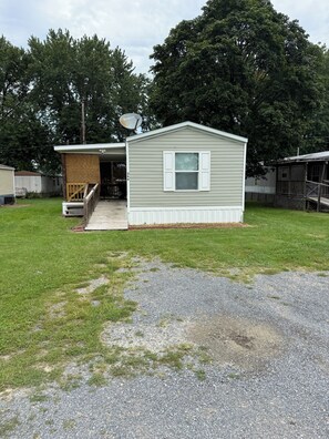 A single-story mobile home with a front porch and a satellite dish.