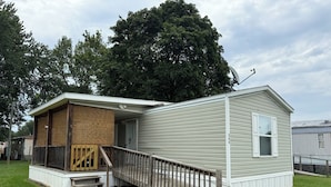 A single-story mobile home with a porch and a small deck.
